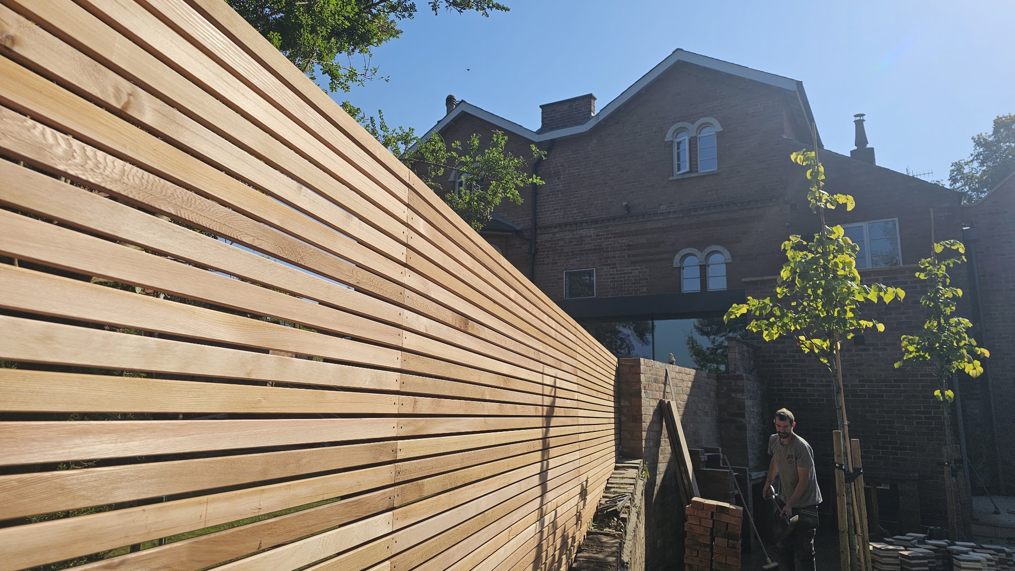 A craftsman beside horizontal timber fencing installed by Vale Fencing Harby